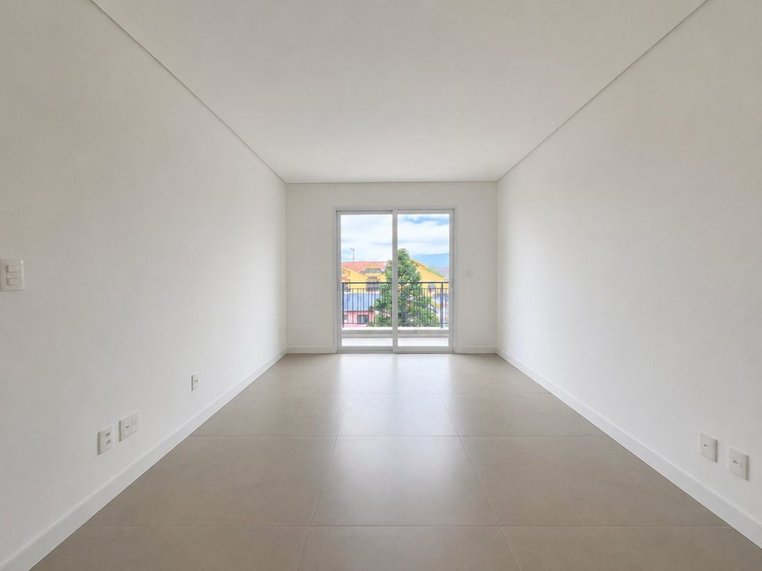 Antes: sala recém-entregue, vazia, com piso cinza e paredes brancas